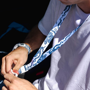 A person in a white shirt wears a Freestyle Lanyard & Key Chain - Octopus by Freestyle while interacting with an object.