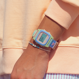 A person in a peach sweatshirt sports a Freestyle SHARK CLASSIC LEASH PEACH DUST watch with 100M water resistance.
